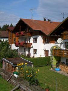 a house with a yard with a fence and flowers at Ferienwohnungen Winter in Lohberg
