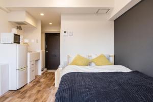 1 dormitorio con 1 cama y nevera blanca en Dwell Urban 6D, en Tokio