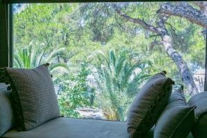 a couch with pillows in front of a large window at Ekies All Senses Resort, a Member of Design Hotels in Vourvourou