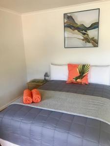 una camera da letto con letto blu e cuscini arancioni di Terraced Chalets a Motueka
