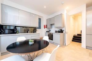 uma cozinha e sala de jantar com uma mesa preta e armários brancos em Spacious and Luxurious London Apartment (MHB352) em Londres