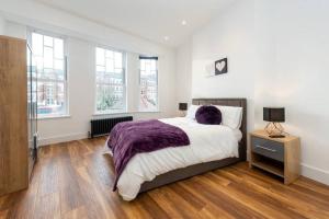 um quarto com uma cama com um cobertor roxo em Spacious and Luxurious London Apartment (MHB352) em Londres