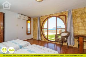 a bedroom with two beds and a chair and a window at SolHabitat Villa Big Blue in Benissa +64 photos