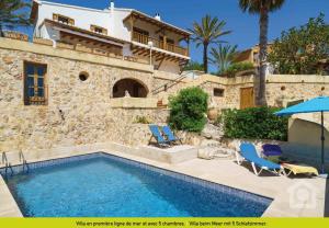 a villa with a swimming pool and two chairs and a house at SolHabitat Villa Papavents in Benissa