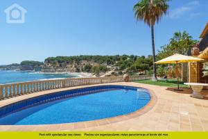 a swimming pool next to a beach with an umbrella at SolHabitat Villa Big Blue in Benissa
