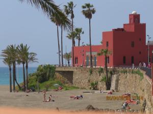a group of people on a beach near a red building at Benal Beach Apartments in Málaga