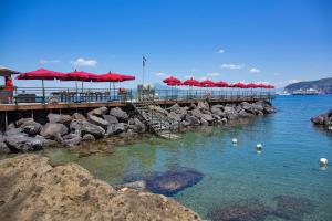 a pier with tables and red umbrellas on the water at Bellevue Syrene in Sorrento