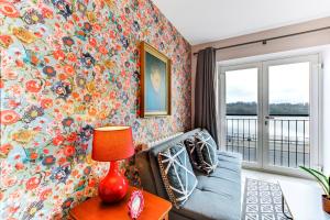 a living room with a blue couch and a floral wall at Riverside Apartment in Derry Londonderry