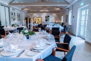 une salle à manger avec tables et chaises et nappes blanches dans l'établissement Vilcon Hotel & Konferencegaard, à Slagelse