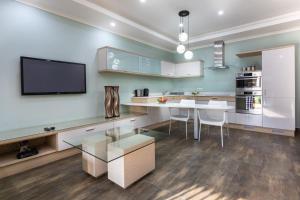 a kitchen with a dining table and a tv on the wall at Fallsway Suites in Lusaka