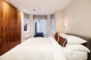 um quarto com uma grande cama branca e uma cabeceira em madeira em Home Sweet Hampstead Heath em Londres