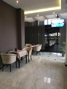 un vestíbulo con mesas, sillas y TV en Ambiance Hotel, en Bucarest