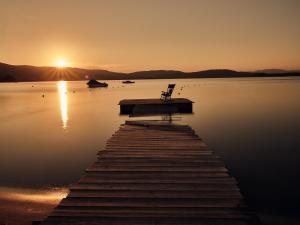 a dock with a chair on the water at sunset at Ekies All Senses Resort, a Member of Design Hotels in Vourvourou