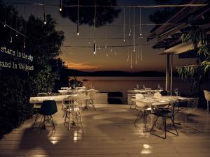 a dining area with tables and chairs at night at Ekies All Senses Resort, a Member of Design Hotels in Vourvourou