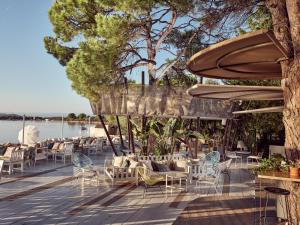a patio with chairs and tables and umbrellas at Ekies All Senses Resort, a Member of Design Hotels in Vourvourou