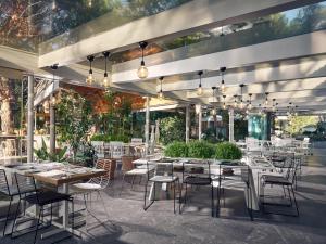 a restaurant with white tables and chairs and windows at Ekies All Senses Resort, a Member of Design Hotels in Vourvourou