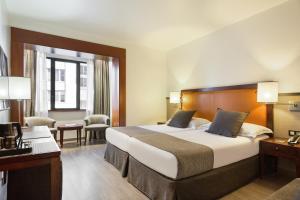 una camera d'albergo con un grande letto e una scrivania di Hotel Balmoral a Barcellona