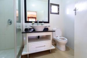 a bathroom with a sink and a toilet and a mirror at Fallsway Apartments - Burley Court in Lusaka