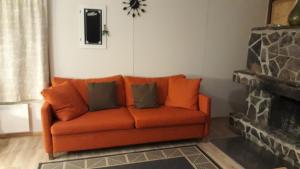 an orange couch in a living room with a fireplace at Holiday Home Ivalo in Ivalo