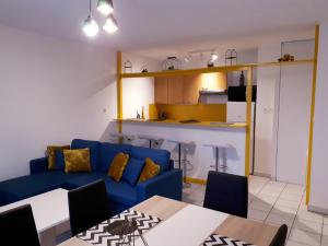 ein Wohnzimmer mit einem blauen Sofa und einer Küche in der Unterkunft Le Venise - Gare Matabiau - T3 - avec Parking Privé in Toulouse