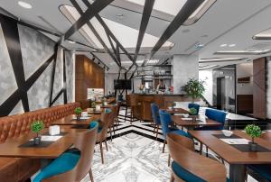 a restaurant with wooden tables and blue chairs at Sky Hotel in Belgrade