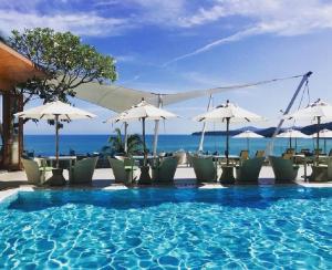 una piscina con sillas y sombrillas y el océano en Cape Sienna Phuket Gourmet Hotel & Villas - SHA Extra Plus, en Kamala Beach
