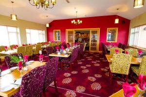 a dining room with tables and chairs and red walls at Curran Court Hotel in Larne