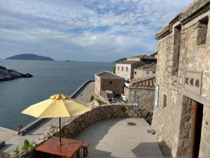 a table with an umbrella on a balcony next to the water at 芹壁德順號民宿Chinbe D S House B&B in Beigan