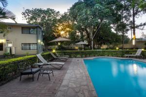 a swimming pool with lounge chairs and a building at Fallsway Apartments - Louden Court in Lusaka