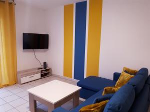 ein Wohnzimmer mit einem blauen Sofa und einem TV in der Unterkunft Le Venise - Gare Matabiau - T3 - avec Parking Privé in Toulouse