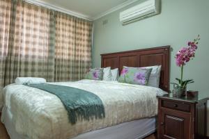 a bedroom with a bed and a vase of flowers at Fallsway Apartments - Louden Court in Lusaka