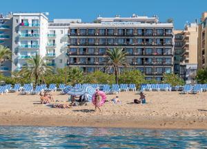 een groep mensen op een strand met een hotel bij Checkin Garbí in Calella