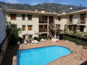 an apartment with a swimming pool in front of a building at Apartamentos Valle del Guadalquivir in Arroyo Frio