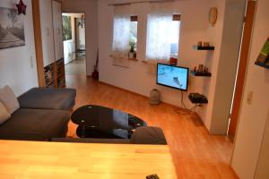 een woonkamer met een bank, een tafel en een tv bij Ferien bei Freunden im Holzhaus in Monschau