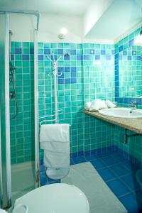 e bagno piastrellato blu con servizi igienici e doccia. di Stella Marina Budoni a Budoni