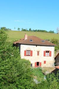 a stone house with red shutters on a hill at Clos de l'Arthonnet in Flavignac