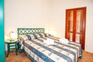ein Schlafzimmer mit einem Bett und einem Tisch mit einer Lampe in der Unterkunft Stella Marina Budoni in Budoni