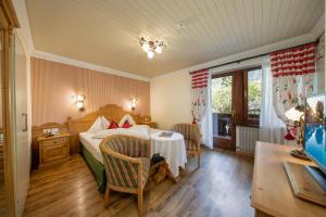 a bedroom with a bed and a table and chairs at PALMENGARTEN Hotel Gstör in Lagundo +37 photos