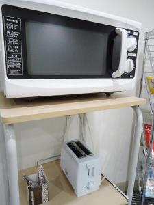 a microwave sitting on top of a wooden shelf at Shin-Okubo City Hotel in Tokyo