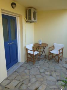 a patio with a table and chairs and a blue door at Vokamvilia Apartments in Kini