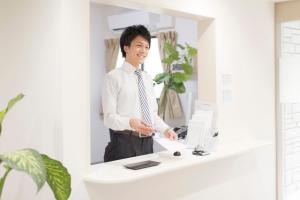 a man standing at a desk in front of a computer at Shin-Okubo City Hotel in Tokyo