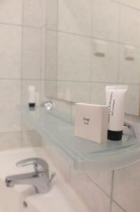 - une étagère en verre dans la salle de bains pourvue d'un lavabo dans l'établissement Motel Subaru, à Varsovie