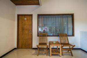 two chairs and a table in a room with a door at Kuta Suci Guesthouse in Kuta