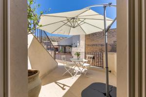 a patio with a table and an umbrella on a balcony at Scicli Albergo Diffuso in Scicli