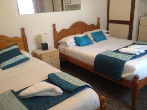 two beds in a hotel room with blue pillows at Sandpiper Guest House in Brighton & Hove