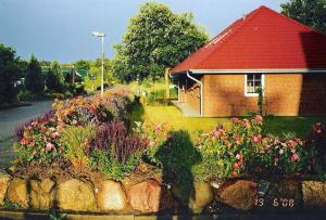 ein Backsteinhaus mit rotem Dach und ein paar Blumen in der Unterkunft FeWo Pülsen in KÃ¶hn