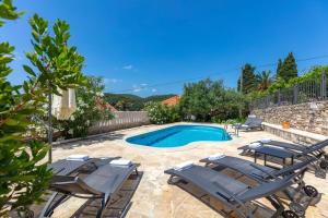 a pool with chaise lounge chairs and a swimming pool at Seafront Serenity Villa Mir Vami - Your Family Oasis by the Shore in Sumartin