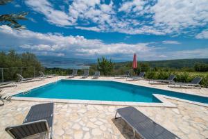 a swimming pool with chairs and a view of the water at Holiday apartment Angelina with Seaview and swimming pool in Sužan