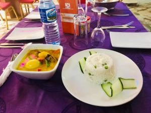 a table with a plate of food and a bowl of rice at Charriot Hotels in Abuja