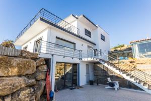 een wit huis met een stenen muur en een trap bij The Maverick Surfvillas in Lourinhã